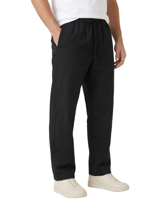 A person wearing black drawstring trousers with a white t-shirt and off-white sneakers, shown from the waist down against a light gray studio background.
