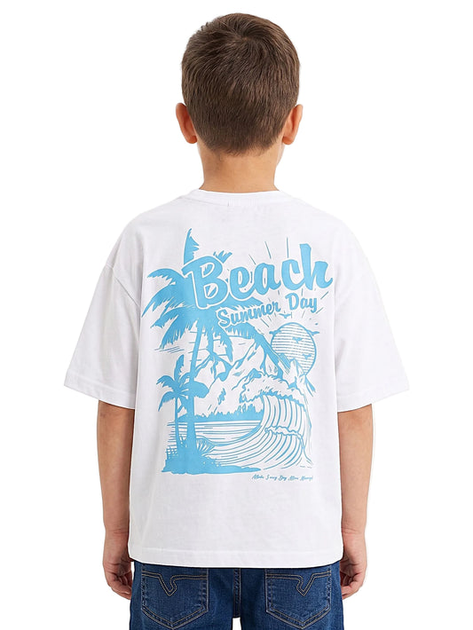 A child viewed from behind wearing a white short-sleeve T-shirt with a large light blue beach graphic on the back that reads 'Beach Summer Day,' paired with blue jeans, against a plain light background.