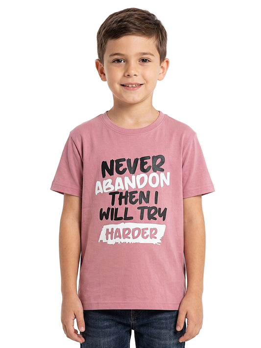 A young boy wearing a pink graphic t-shirt with the text 'NEVER ABANDON THEN I WILL TRY HARDER' in black and white lettering, paired with dark blue jeans, photographed against a plain white background.