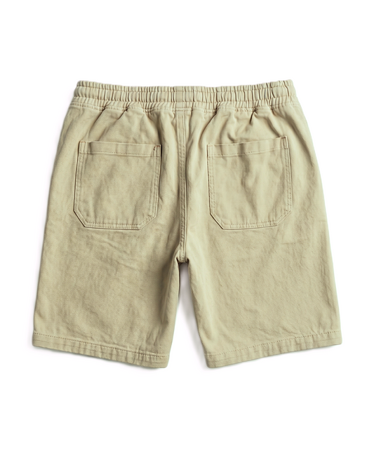 A pair of light khaki or beige shorts shown from the back, featuring an elastic waistband and two large patch pockets, laid flat on a white background.