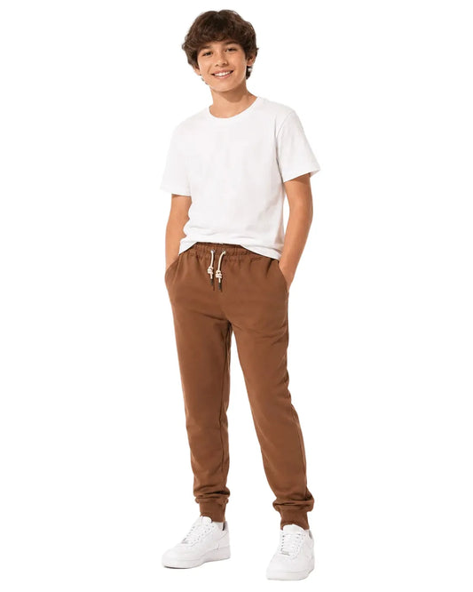 Front view of a young boy wearing brown jogger sweatpants by TREE.