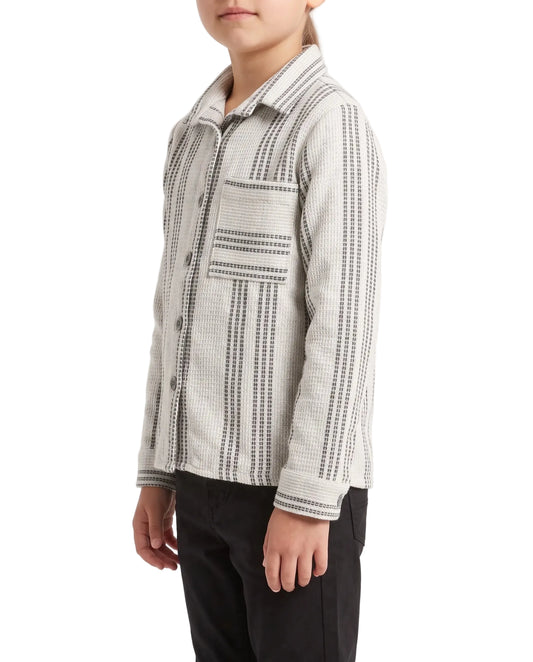A child wearing a light gray and black patterned button-up shirt with black pants, photographed against a plain white studio background.