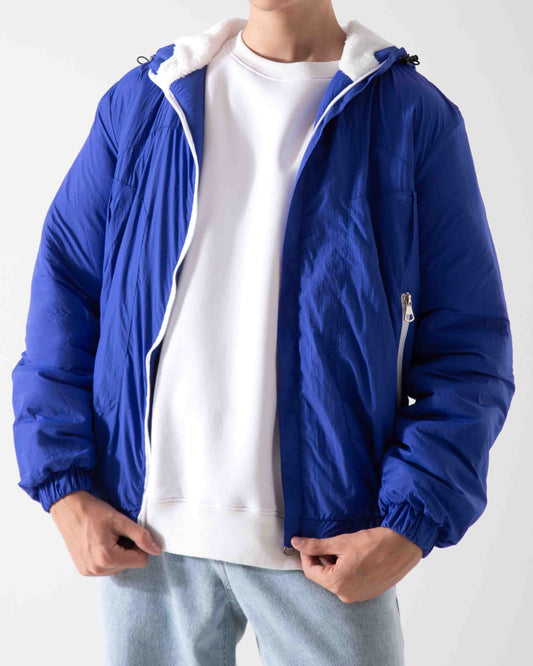 Person wearing a blue jacket over a white shirt on a plain background