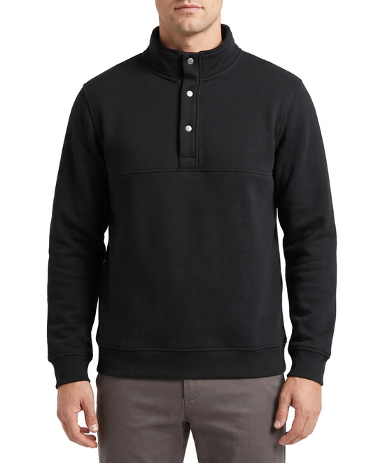 A man wearing a black long-sleeve mock neck pullover sweatshirt with a three-button placket, paired with gray trousers, against a plain white background.