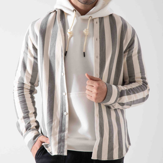Person wearing a striped shirt over a white hoodie on a plain background