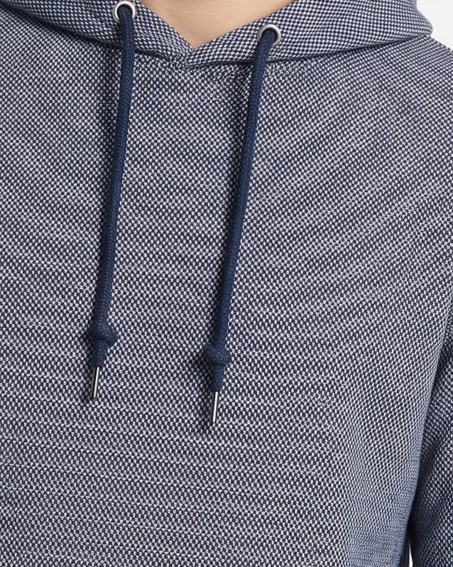 Close-up of a textured navy and gray hooded sweatshirt with dark navy drawstrings and silver metal eyelets.