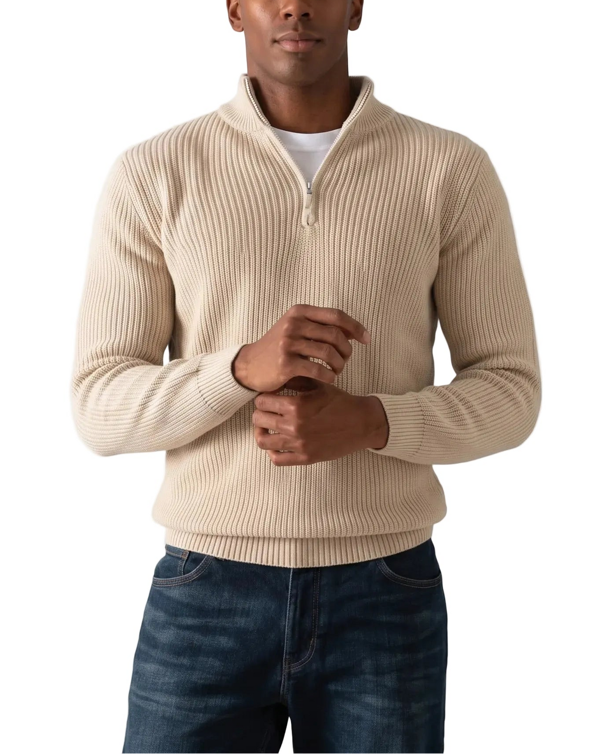 A man wearing a beige ribbed quarter-zip sweater over a white t-shirt and dark blue jeans, standing against a plain white background.