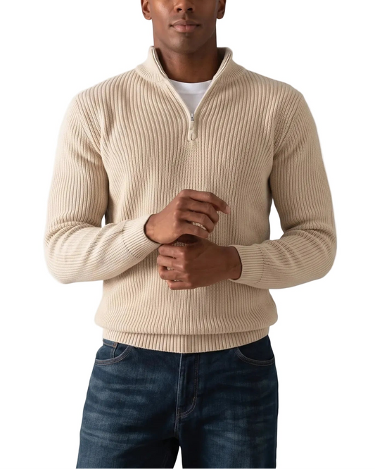 A man wearing a beige ribbed quarter-zip sweater over a white t-shirt and dark blue jeans, standing against a plain white background.