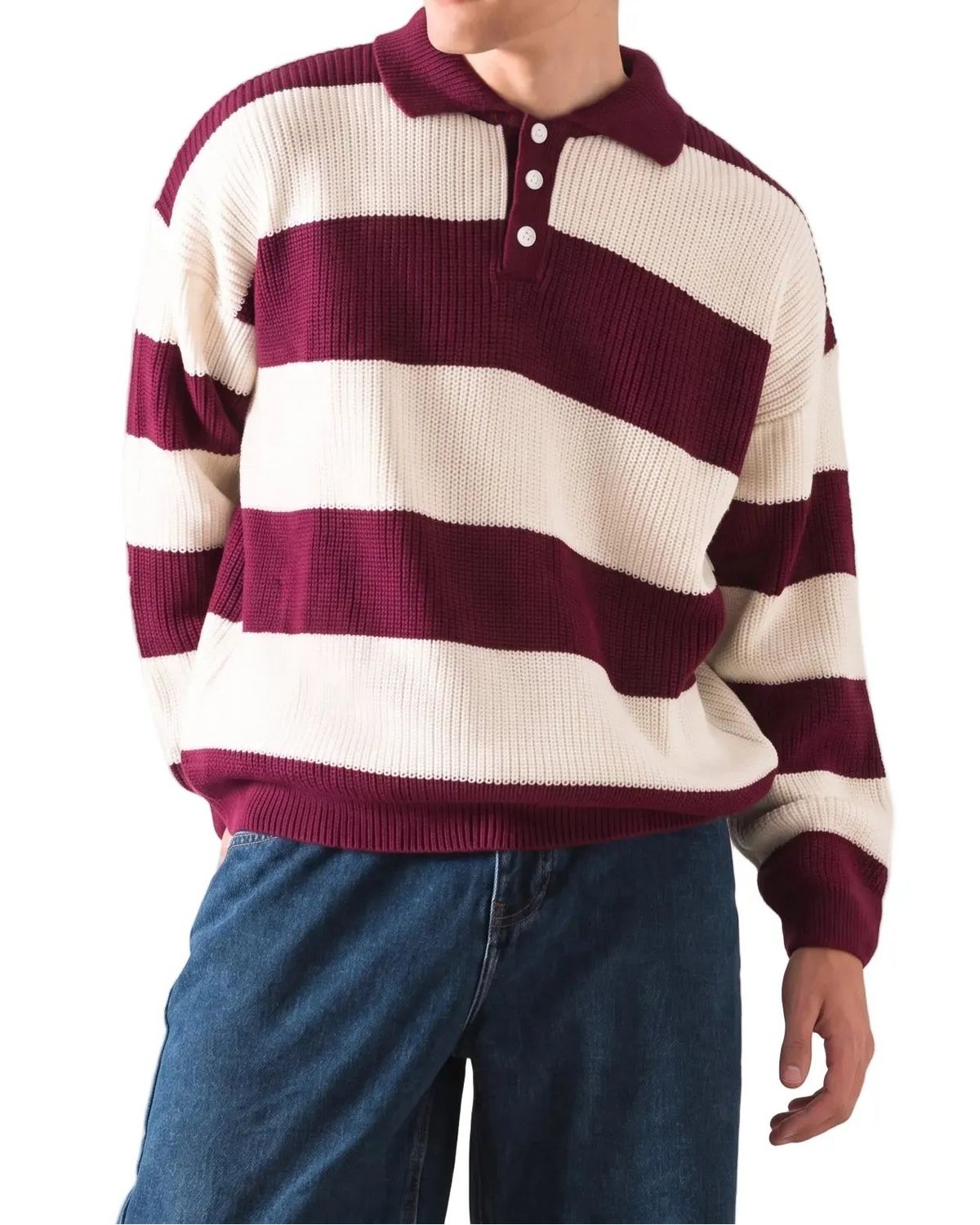 A young man wearing a maroon and cream striped knit polo sweater with blue jeans, photographed against a plain white studio background.