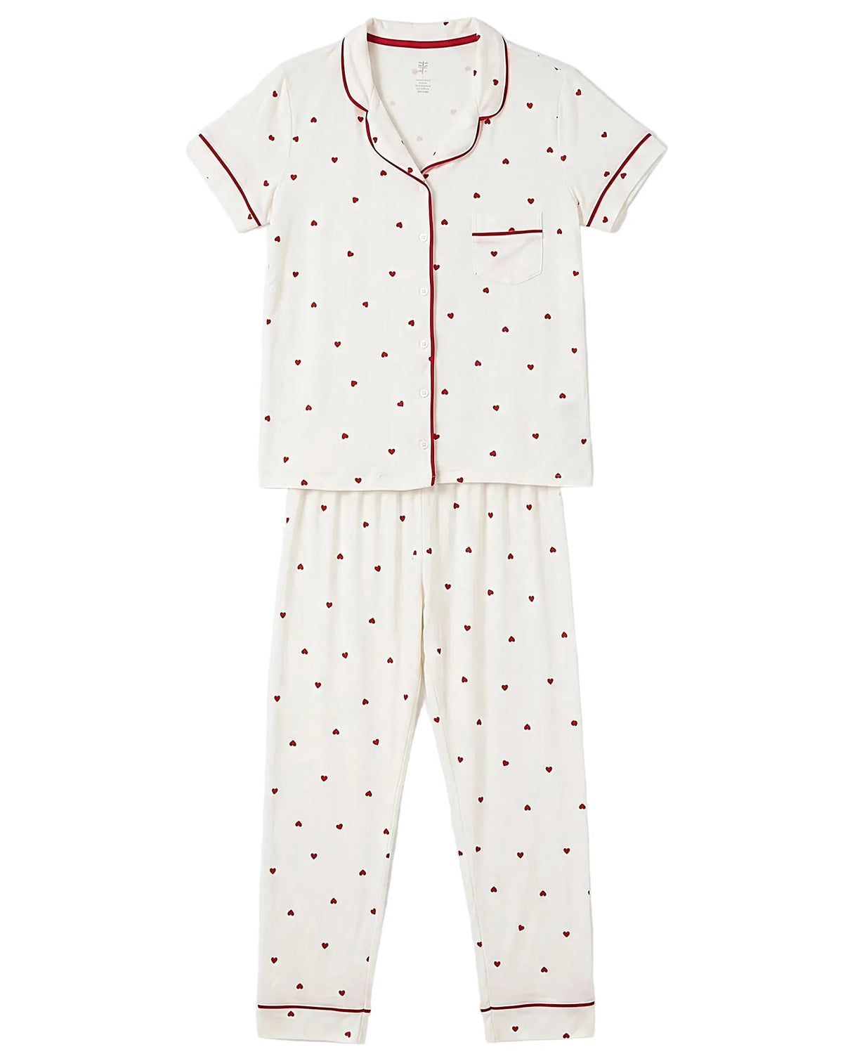 Front view of a women's creamy white two-piece pajama set featuring an all-over red heart print and contrast piping, including a short-sleeve button-down shirt and lounge pants by TREE.