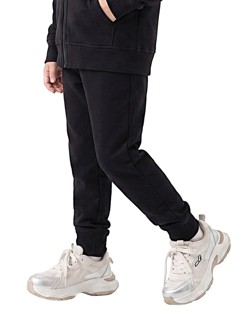 Side view of a young girl wearing black milton pants in a relaxed fit by TREE.