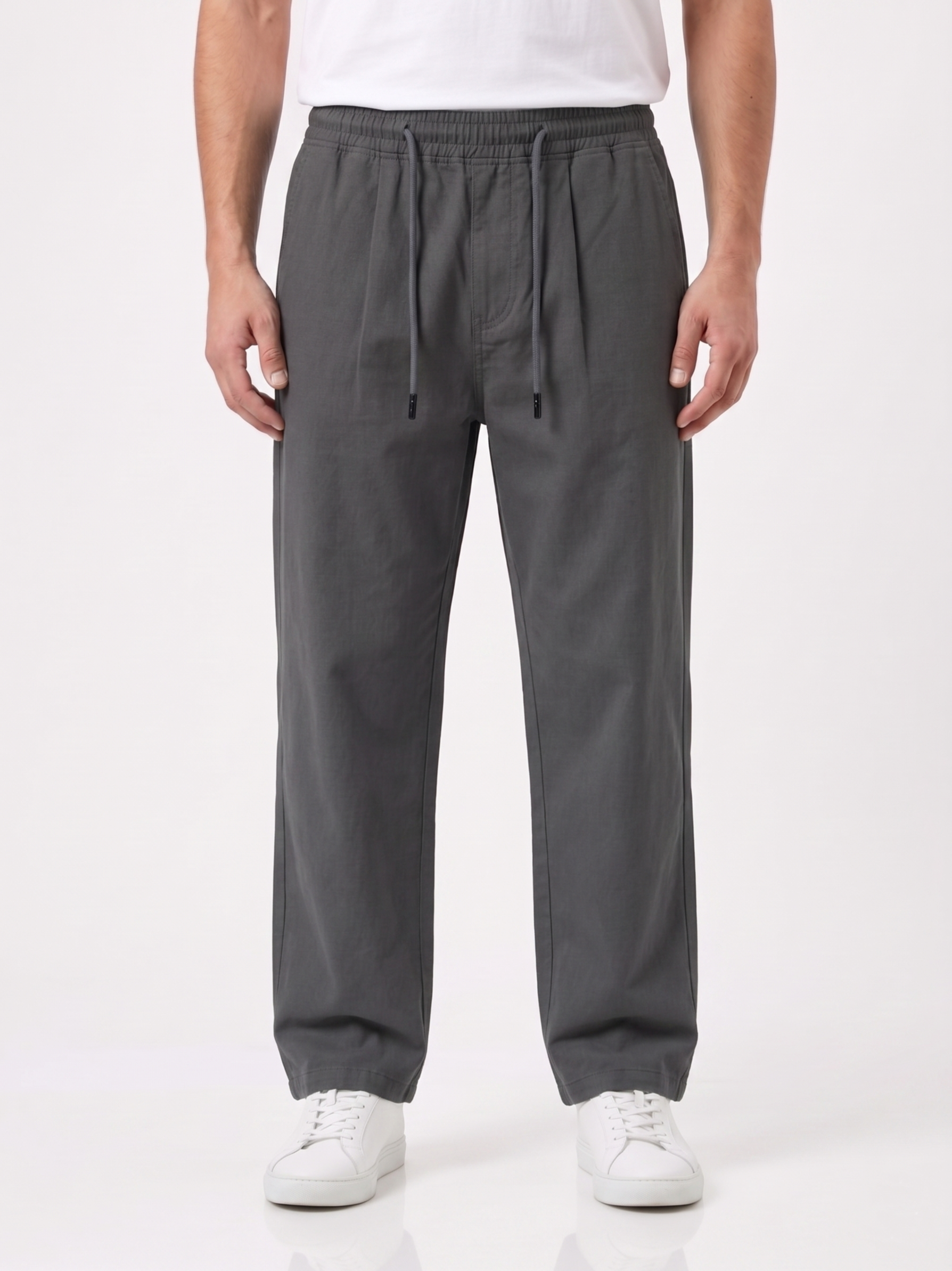 Person wearing gray pants and white shoes on a white background