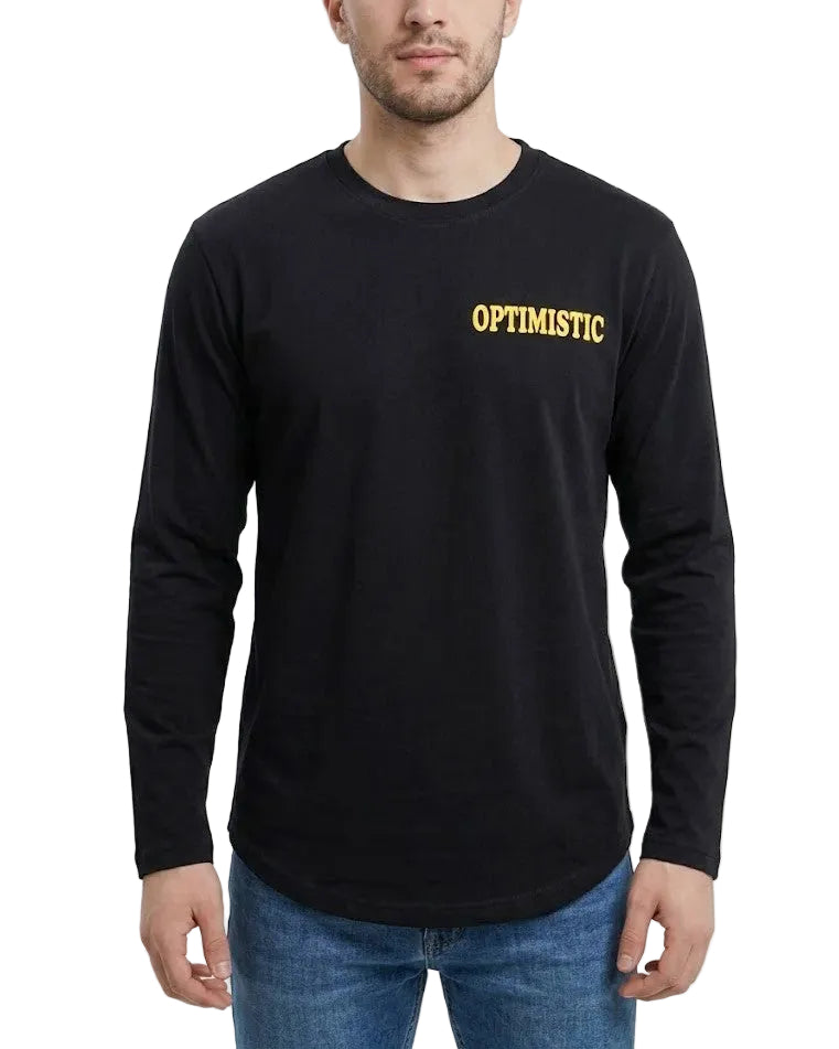 A man wearing a black long-sleeve t-shirt with 'OPTIMISTIC' printed in yellow across the chest, paired with blue jeans, against a plain light gray background.