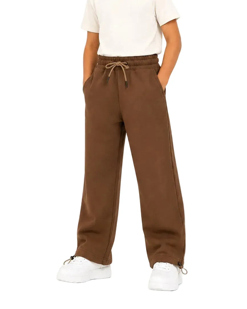 Front view of a child wearing brown kids' wide leg sweatpants with side pockets and a drawstring waist by TREE.