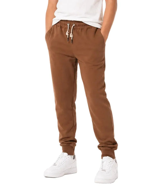 Front view of a young boy wearing brown jogger sweatpants by TREE.