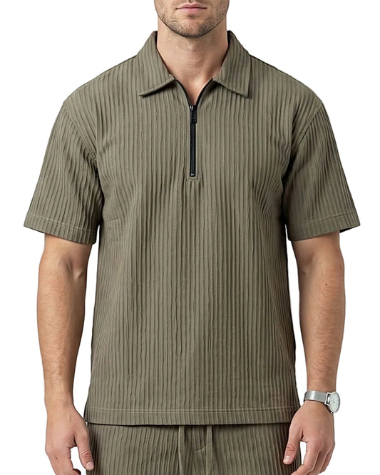 A man wearing a short-sleeve quarter-zip polo shirt in olive green with vertical ribbed texture, paired with matching ribbed trousers, against a light gray studio background.