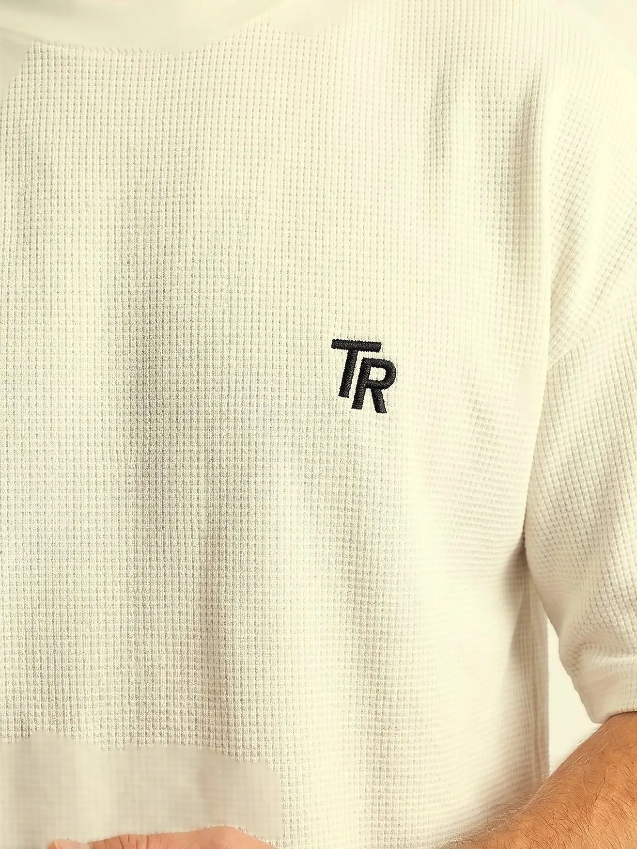 Fabric Detail Image: Close-up showing the visible cotton texture and the precise TR embroidery on the chest.
Sleeve Detail Image: Angle showing the relaxed oversized fit and drop shoulder design of the men's t-shirt.