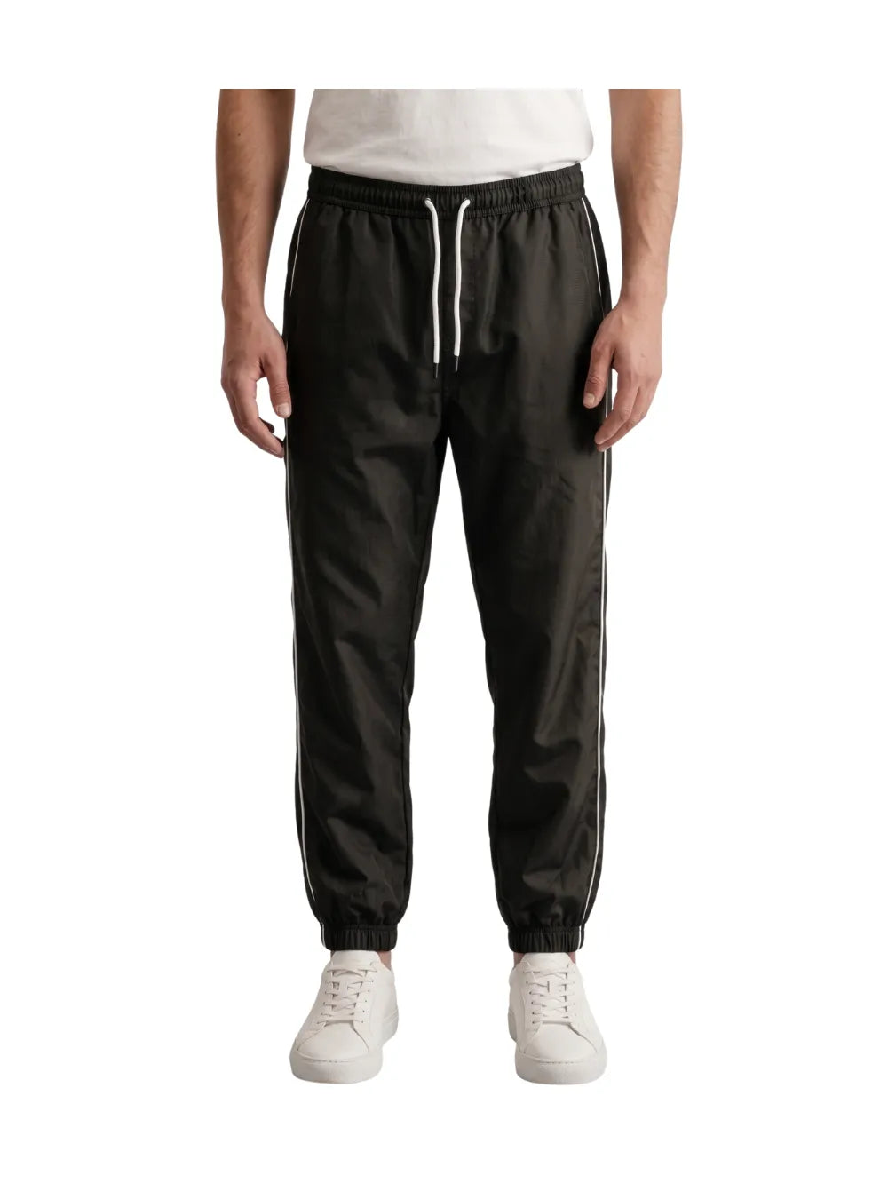 Front view of a man wearing dark grey athletic track pants with white side stripes by TREE