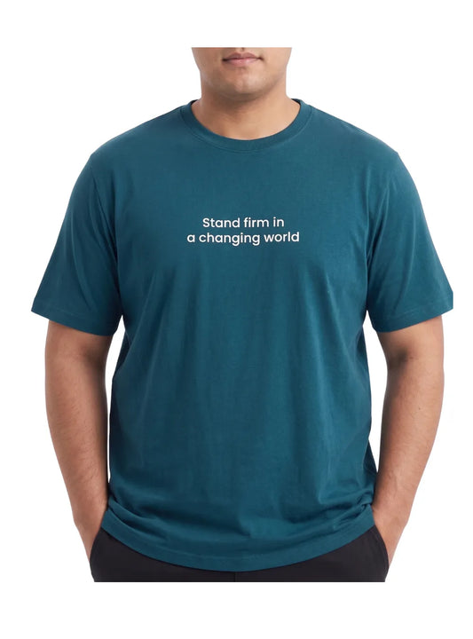 Front view of a man wearing a big size petroleum t-shirt with "Stand firm" print by TREE.