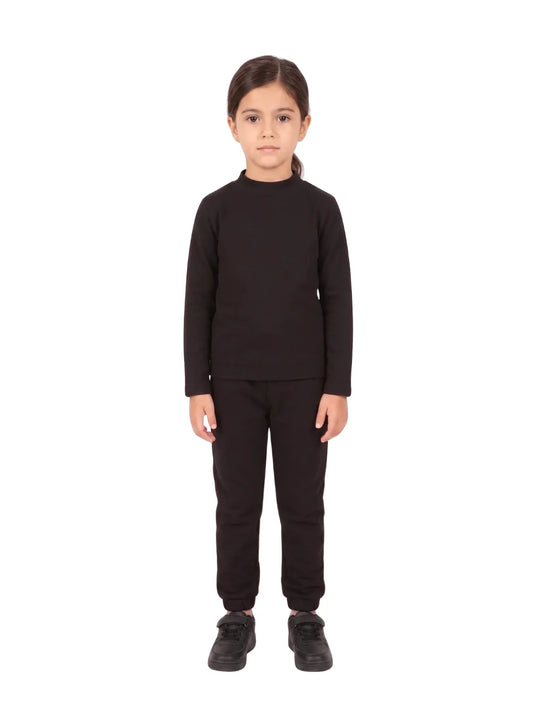 "Full-body front view of a young smiling girl wearing a Girls' Black High-Neck Basic Top with matching black pants and white sneakers against a white background