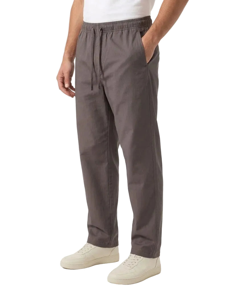 A person wearing dark gray drawstring trousers with side pockets, paired with a white t-shirt and off-white sneakers, shown from the waist down against a plain white studio background.