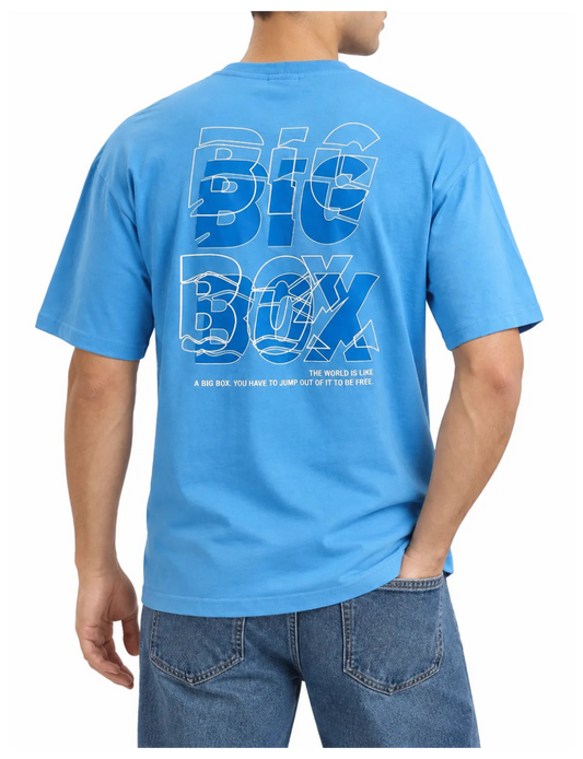 A man wearing a bright blue t-shirt from the back, featuring a large graphic print that reads 'BIG BOX' in layered white and blue outlines, with smaller text underneath. He is also wearing blue jeans against a plain white background.