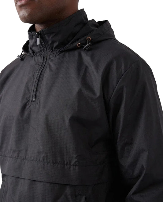 Close-up of a person wearing a black hooded half-zip anorak jacket against a plain light gray background.