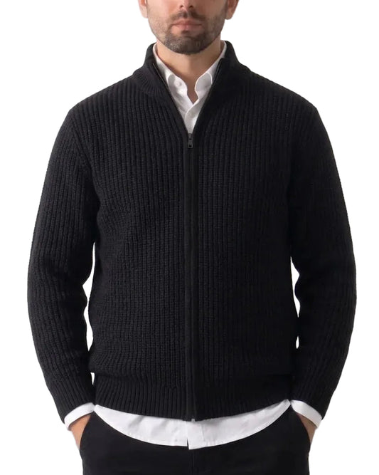 A man wearing a black ribbed knit zip-up cardigan over a white collared shirt, shown from the chin down against a plain white background.