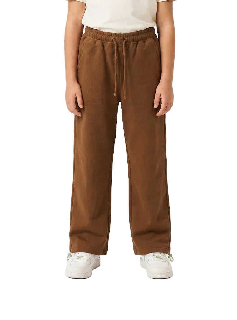 A person wearing brown wide-leg drawstring sweatpants with a cream t-shirt and white sneakers, shown from the waist down against a plain white studio background.