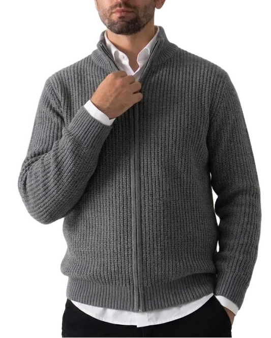 A man wearing a gray ribbed knit zip-up sweater over a white collared shirt, standing against a plain light background.