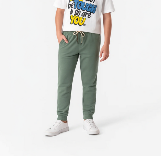 Person wearing a white t-shirt with colorful text and green pants on a white background