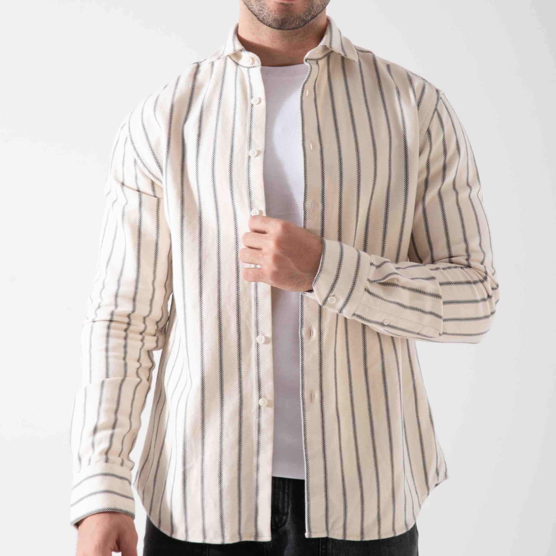 Man wearing a beige and white striped shirt over a white t-shirt on a white background