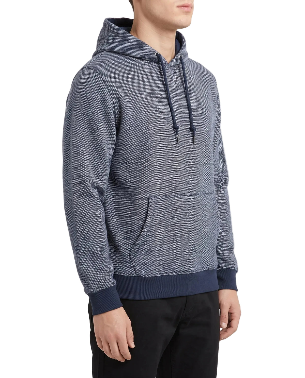 A man wearing a textured heathered blue hoodie with dark navy ribbed cuffs, hem, and drawstrings, paired with black pants, photographed against a clean white studio background.