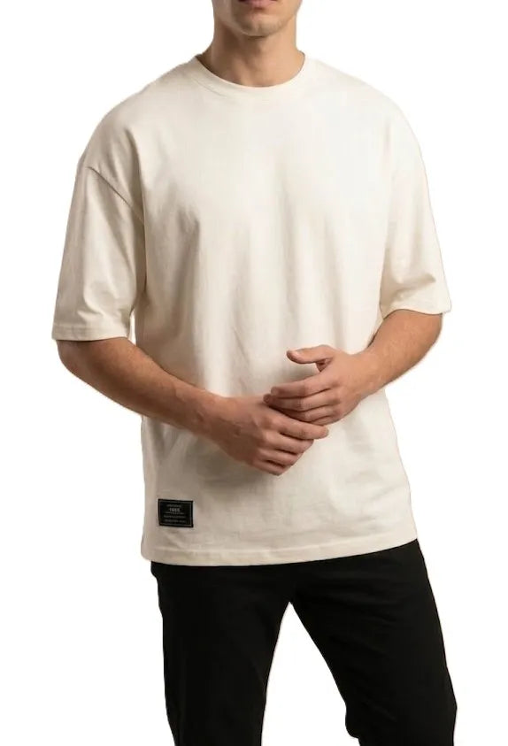 Close-up of the small black patch on the bottom hem of TREE's off-white t-shirt