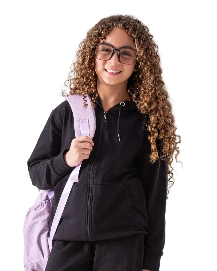 Front view of a girl wearing a black zip-up hoodie with a hood and front pockets by TREE.